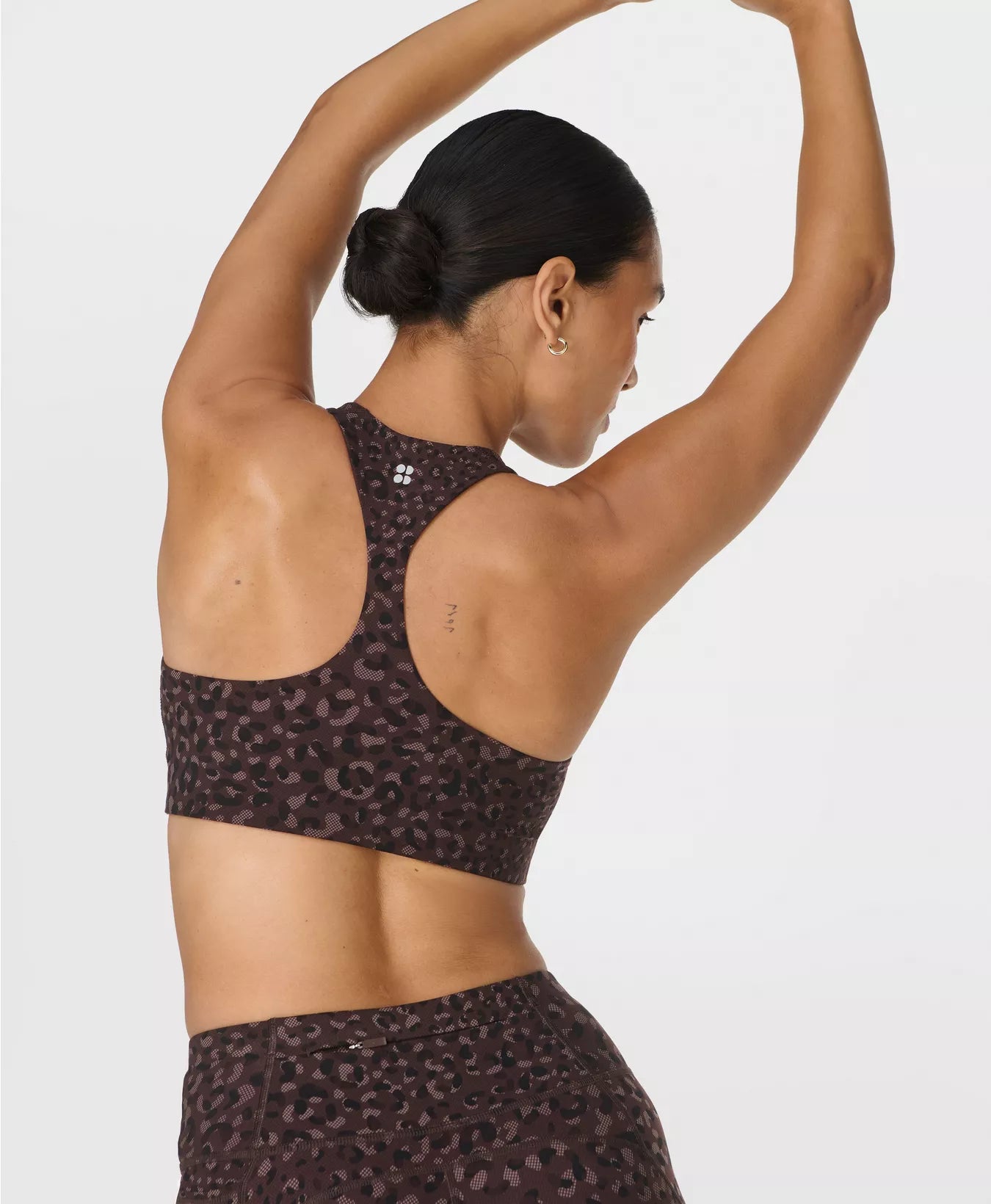 Person wearing a leopard print sports bra and leggings on a light gray background
