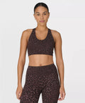 Woman wearing a brown leopard print sports bra and leggings on a white background