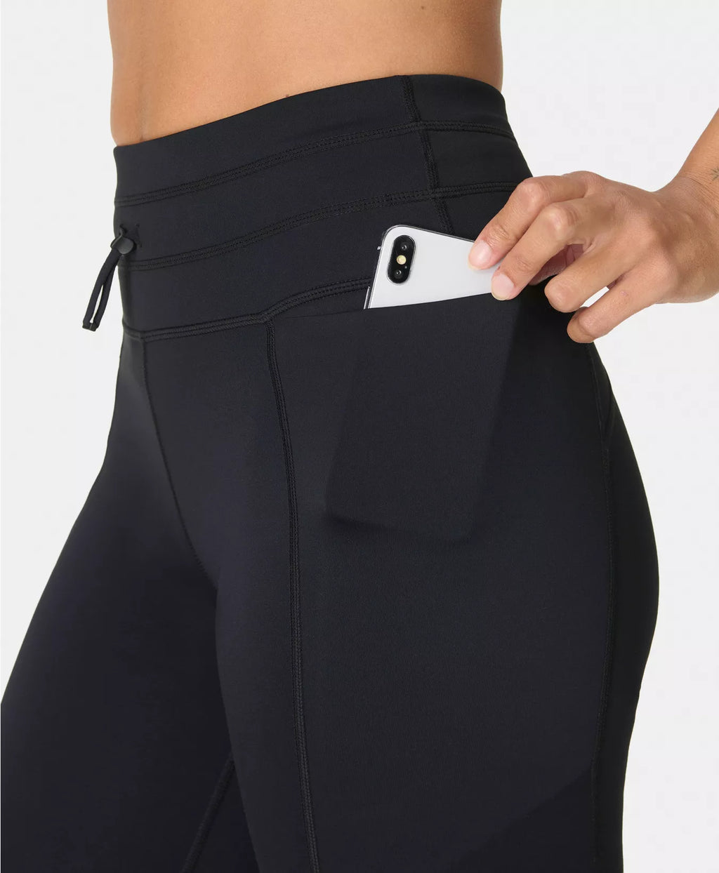 Person wearing black pants with a pocket, holding a phone.