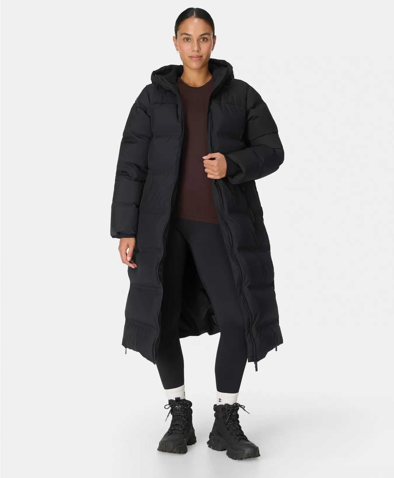 Person wearing a long black puffer coat on a white background