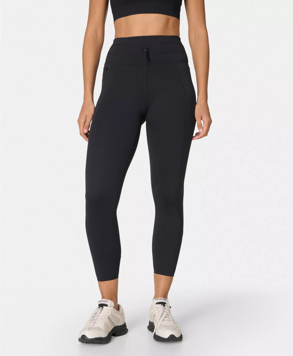 Person wearing black leggings and a black crop top on a white background