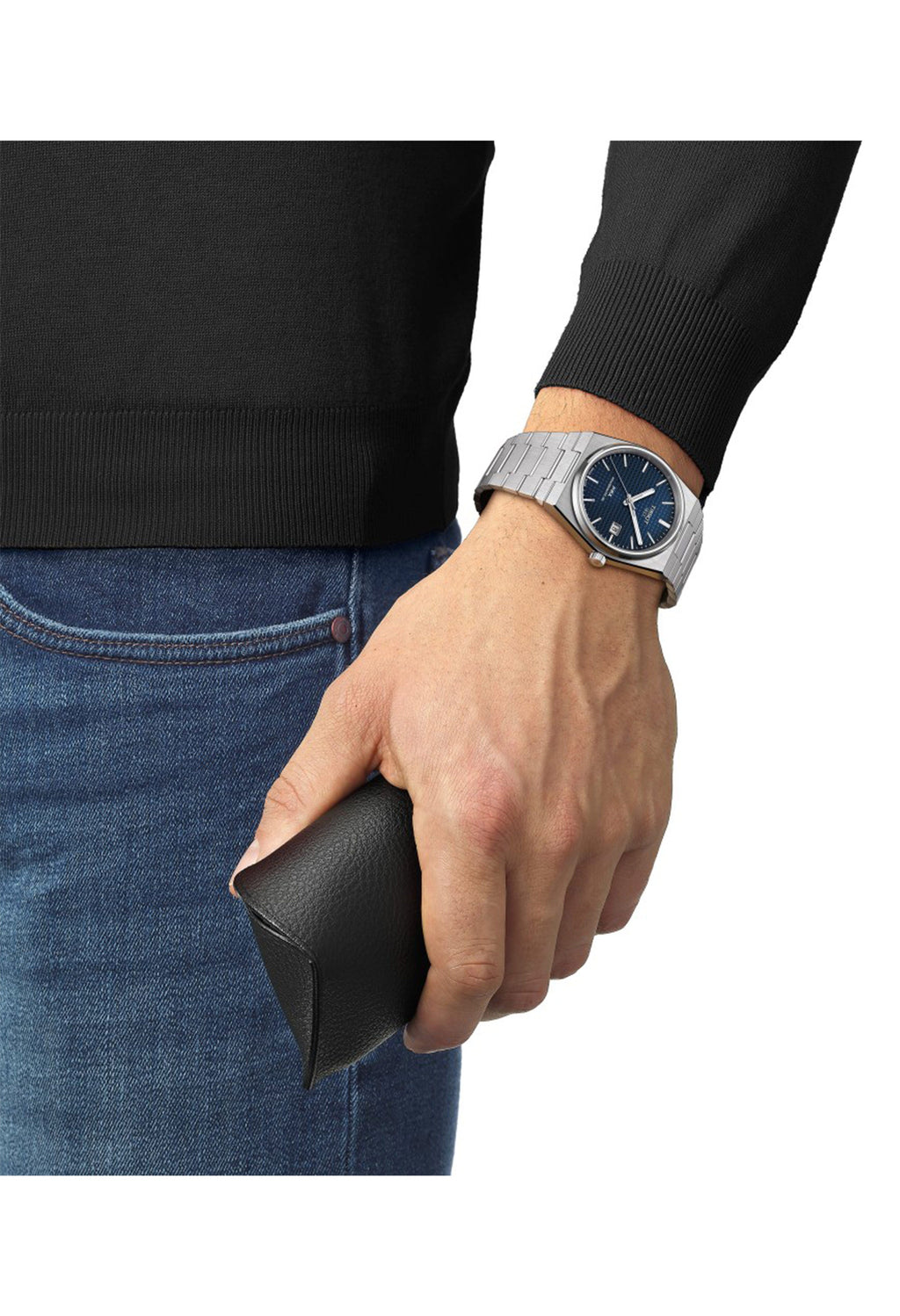Man wearing Tissot PRX watch with blue dial and steel bracelet, holding a case. Style and elegance.