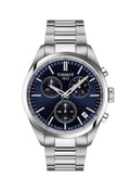 Close-up of the Tissot PR100 chronograph watch, showcasing the blue dial, stainless steel bracelet, and date window. Tissot