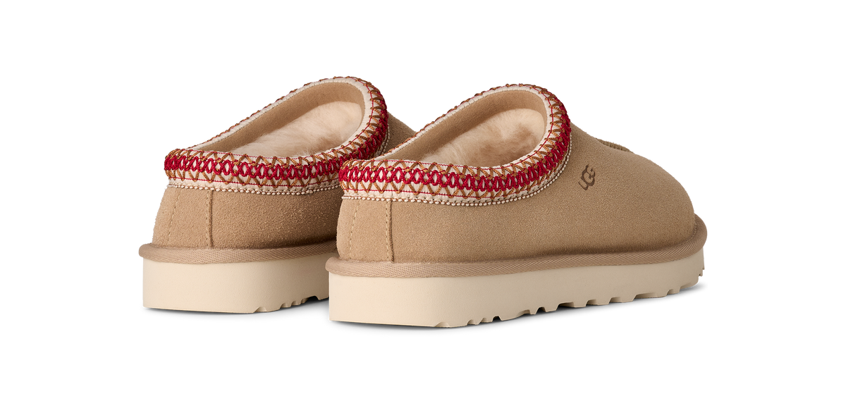 Beige UGG slippers with red trim on a white background