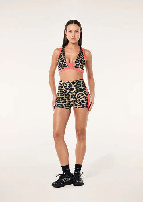 Woman wearing a leopard print sports bra and shorts set on a white background