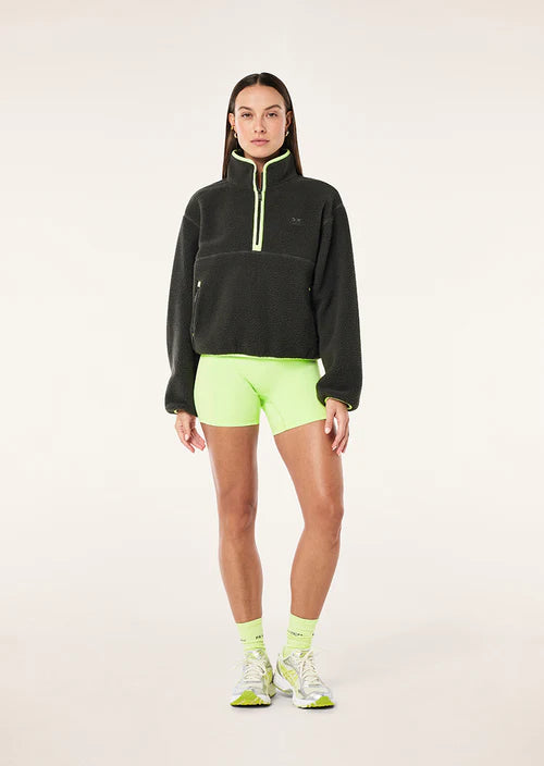 female model wearing  a grey teddy fleece with lime green highlights on a white background