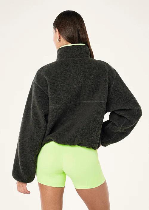 female model wearing  a grey teddy fleece with lime green highlights on a white background