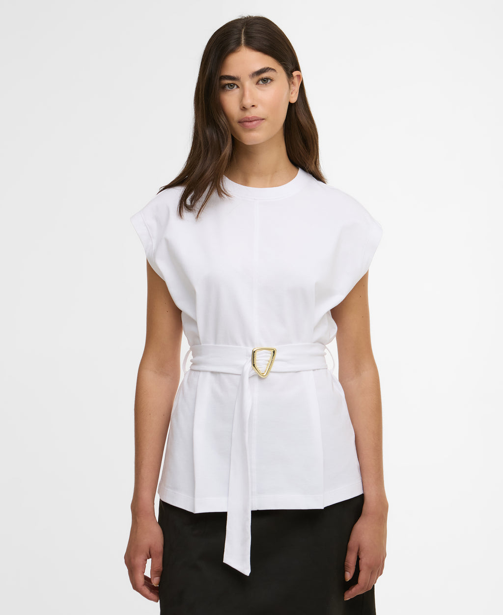 Woman wearing a white top with a belt on a plain background
