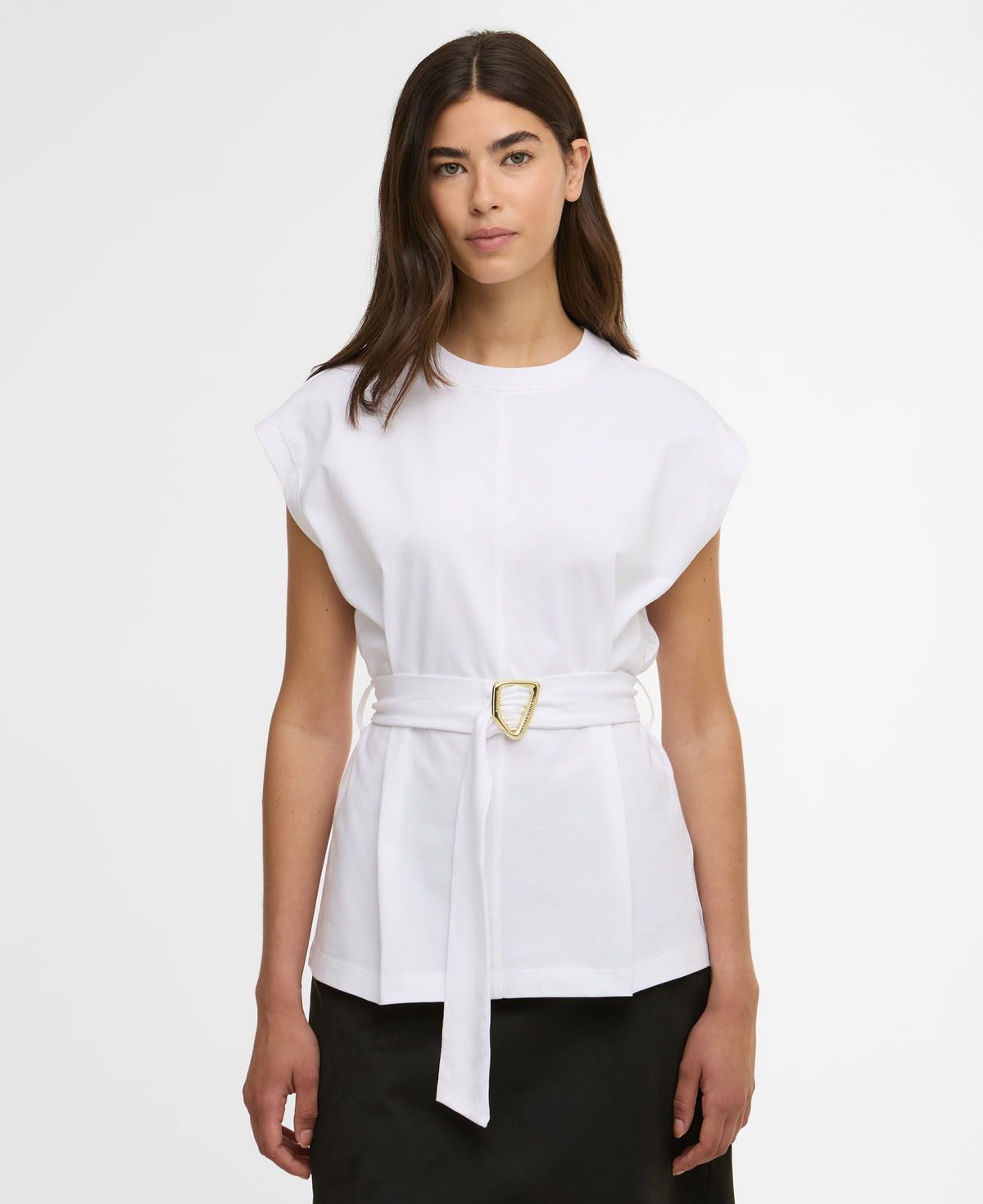 Woman wearing a white top with a belt on a plain background