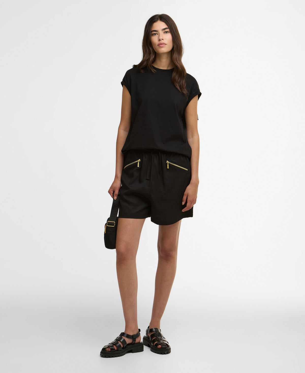 Woman wearing a black outfit with shorts and a top on a white background