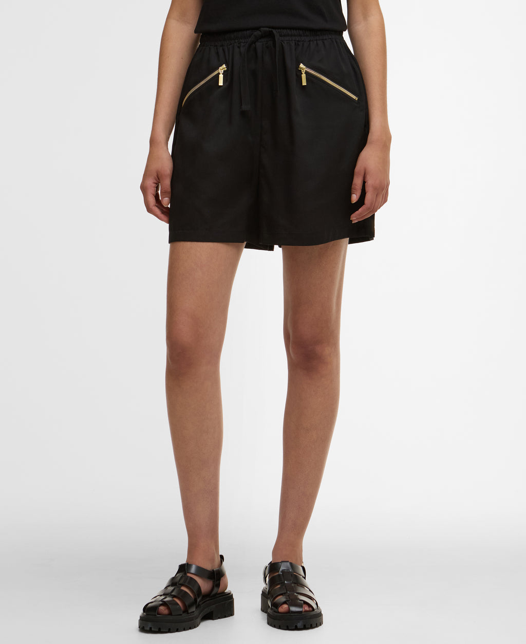 Black shorts with gold zippers worn by a person on a white background
