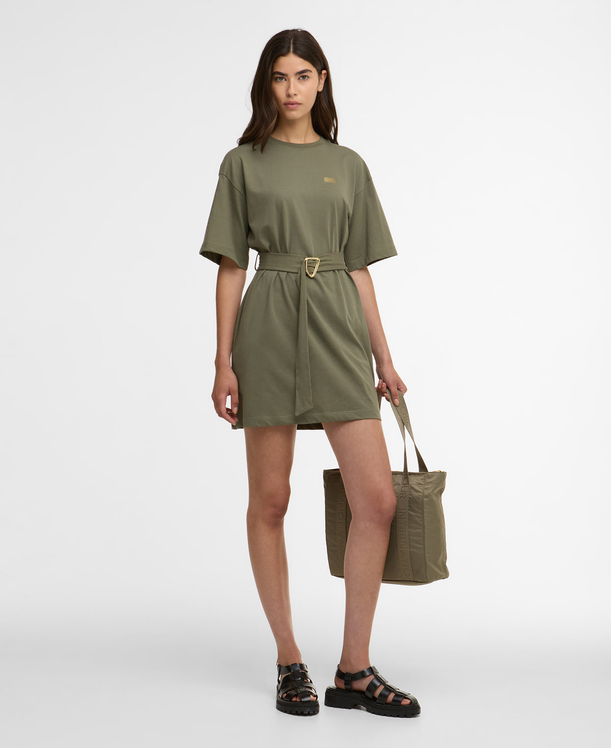 Woman wearing a green dress holding a matching bag on a white background