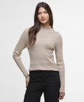 Woman wearing a beige ribbed sweater with a plain background