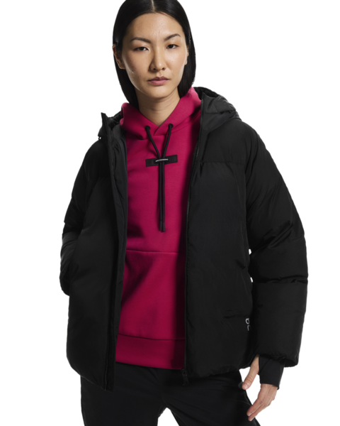 Person wearing a black jacket over a pink hoodie on a white background