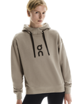 Person wearing a beige hoodie with a logo on a white background
