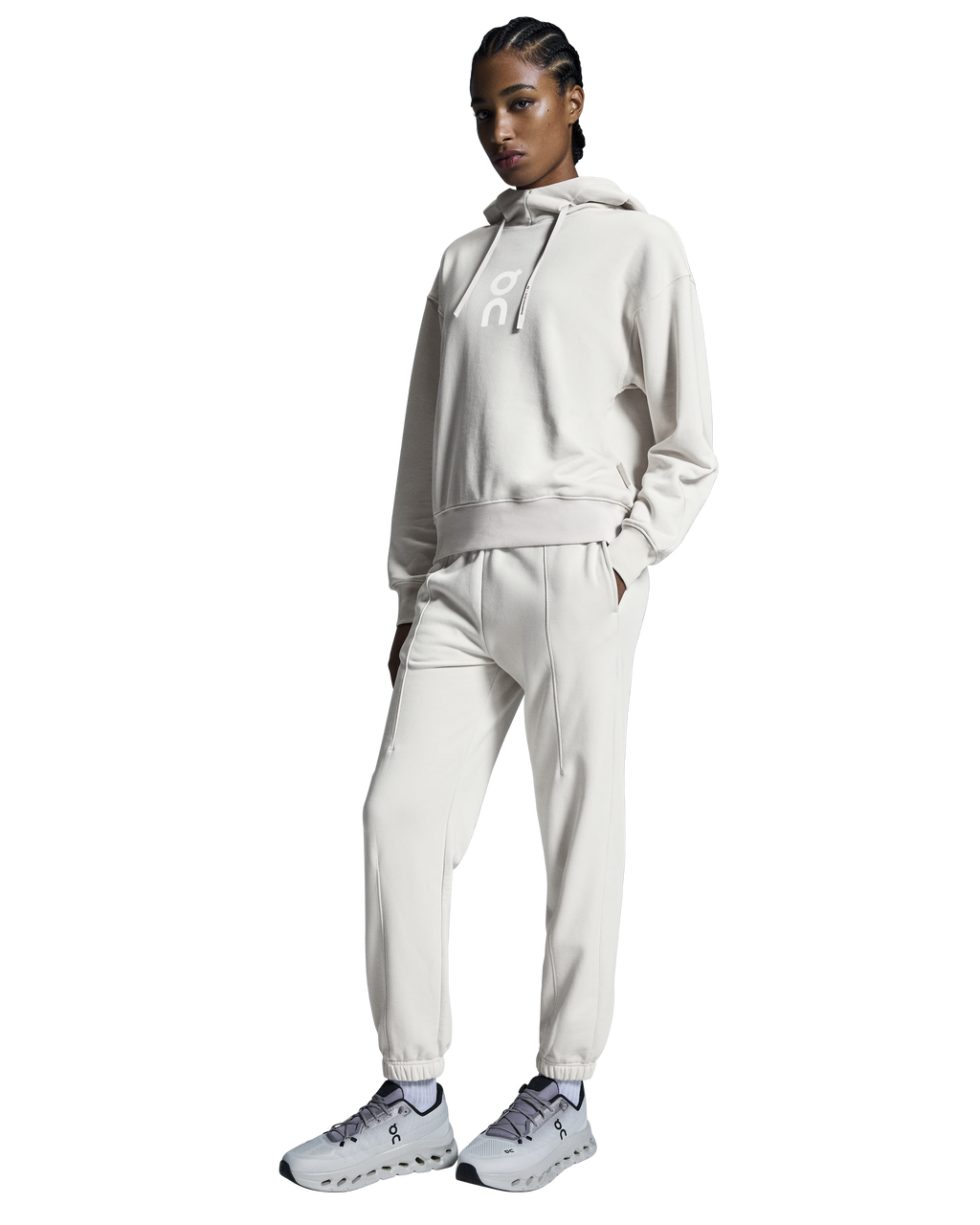 A woman standing, wearing a silver hoodie and matching silver pants with a relaxed fit, designed for running or leisure activities.