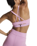 Person wearing a pink sports bra and leggings on a white background