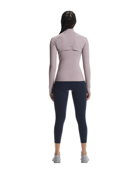 Person wearing a light purple long-sleeve top and dark blue leggings on a white background