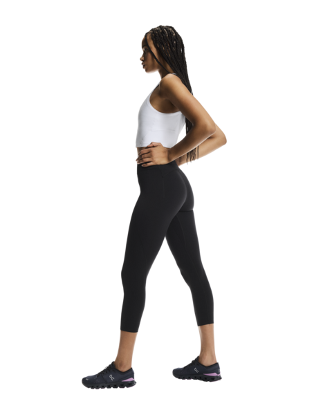 Woman wearing a white tank top and black leggings on a white background