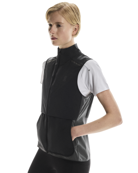 Woman wearing a black and gray vest gilet over a white shirt on a white background