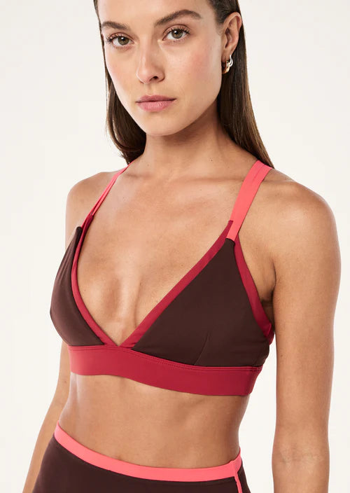 Woman wearing a brown and pink sports bra on a white background