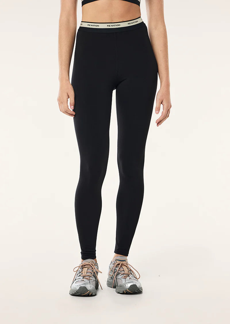 Person wearing black leggings with a beige  waistband on a light grey background