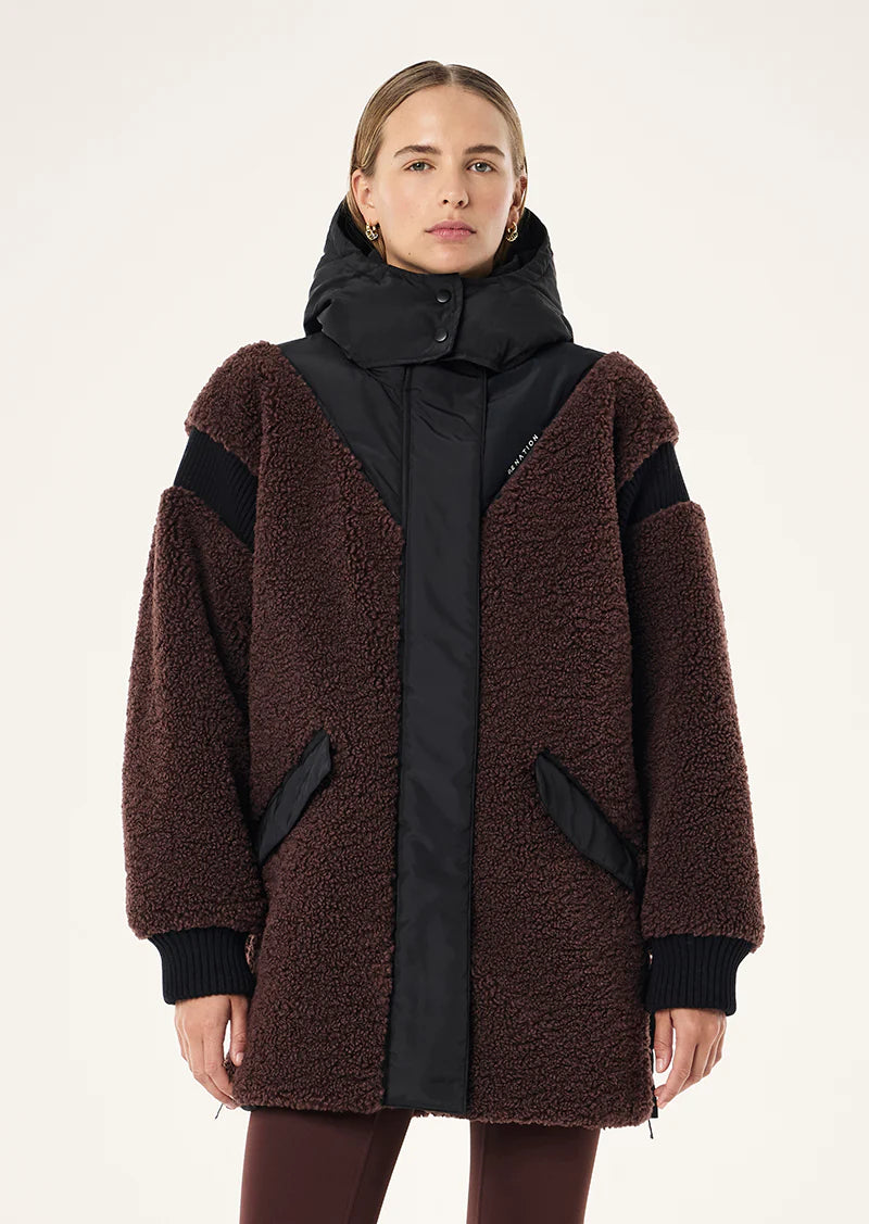 Woman wearing a brown and black coat with a hood on a white background