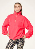 Woman wearing a bright pink jacket with a brand logo on a white background