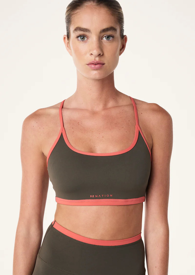 person wearing a Women's P.E Nation Fundamental Tarmac/Brick Red Sports Bra with a white background 
