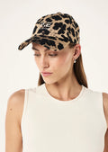 Woman wearing a leopard print cap with branding on a white background
