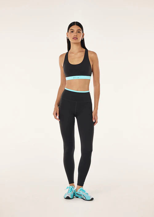 Woman wearing a black sports bra and leggings with blue accents on a white background