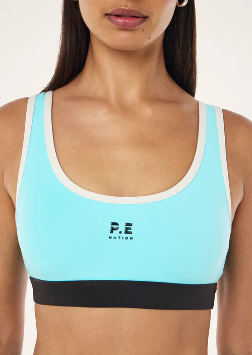 Light blue sports bra with black band and 'P.E Nation' logo on a plain background