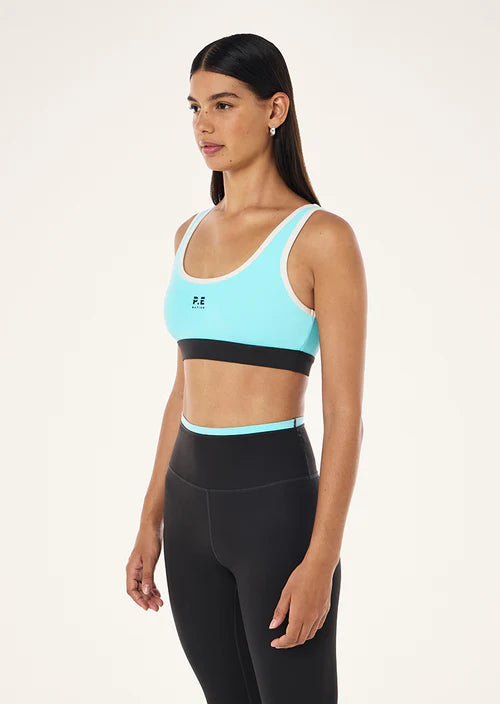 Woman wearing a light blue sports bra and black leggings on a white background