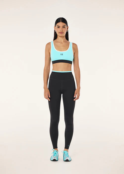 Woman wearing a light blue sports bra and black leggings on a white background