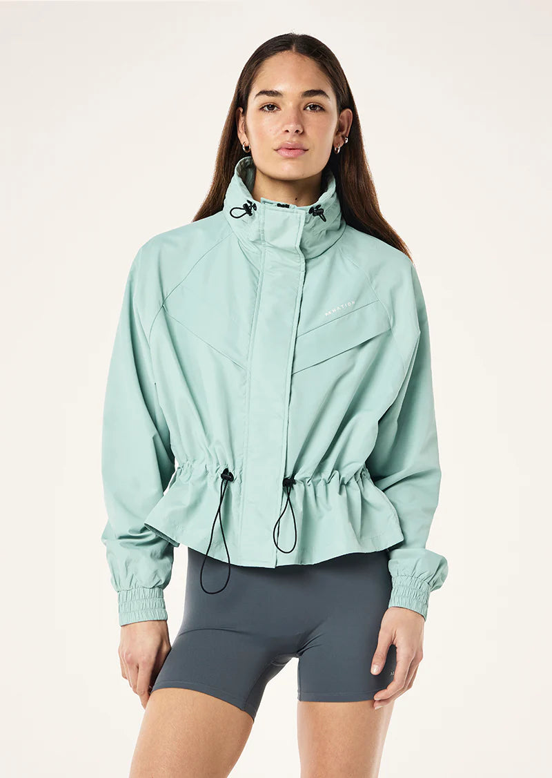 Woman wearing a light blue jacket and dark gray shorts on a white background