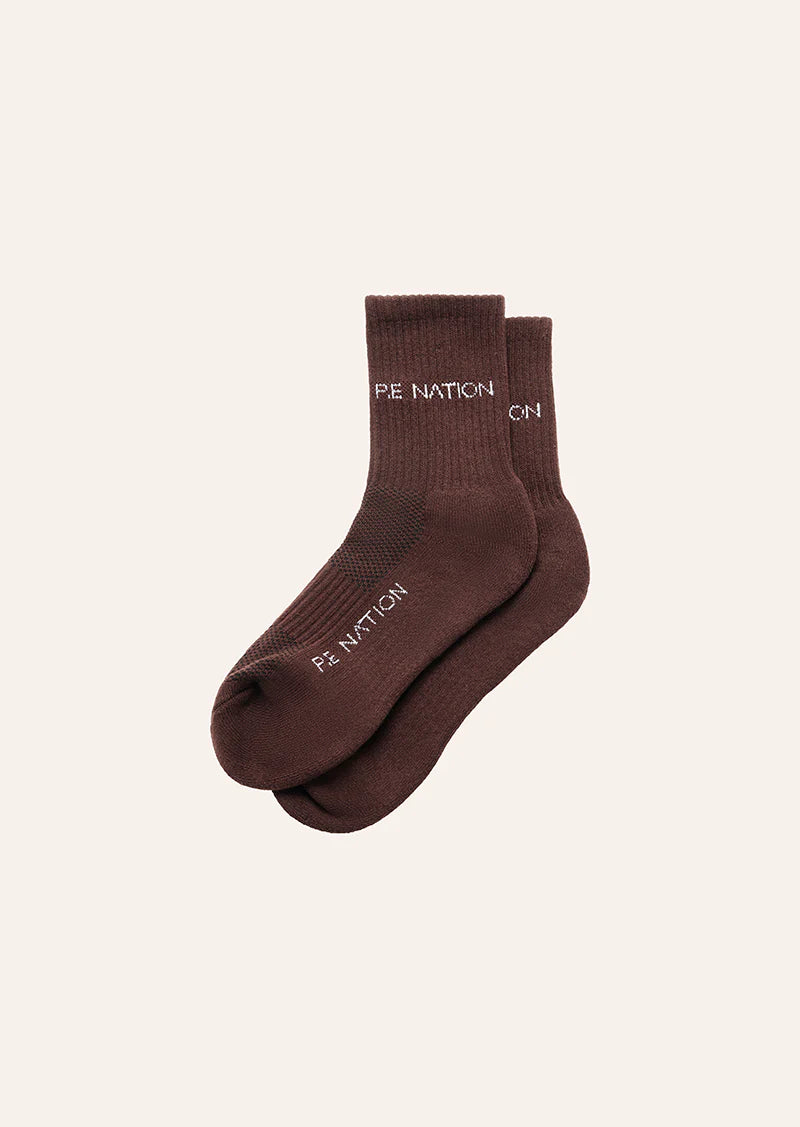 Pair of brown socks with 'PE Nation' branding on a beige background