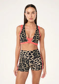 Woman wearing a leopard print sports bra and shorts with pink accents on a white background