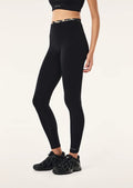 Person wearing black leggings and black sneakers on a white background