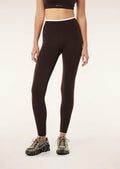 Person wearing brown and pink leggings and a brown sports bra on a white background