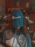 Person wearing a blue 'Red Run' cap and jacket in an indoor setting