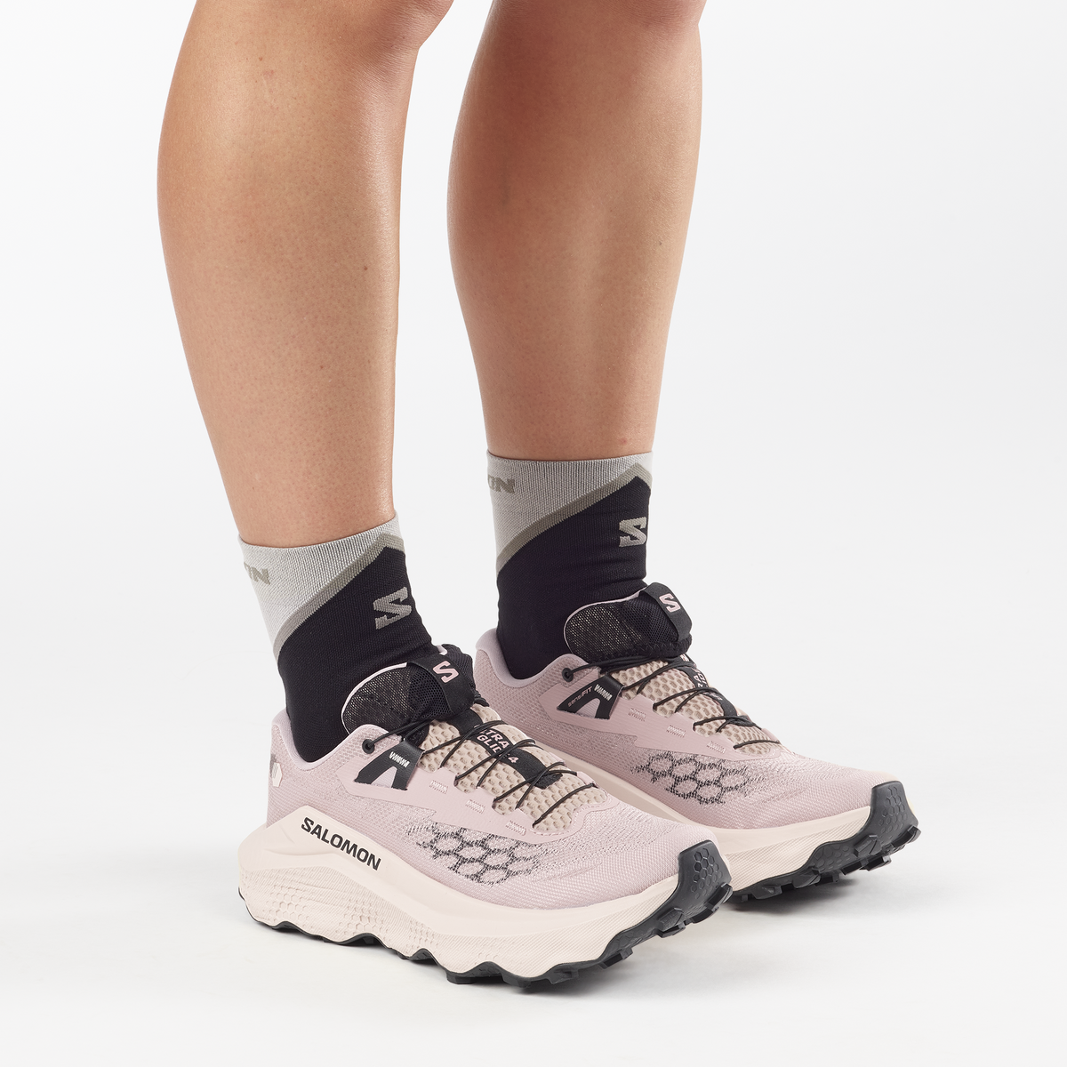 Person wearing Salomon running shoes and socks on a white background
