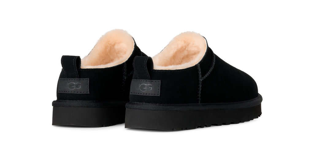 Pair of black slippers with beige interior on a white background