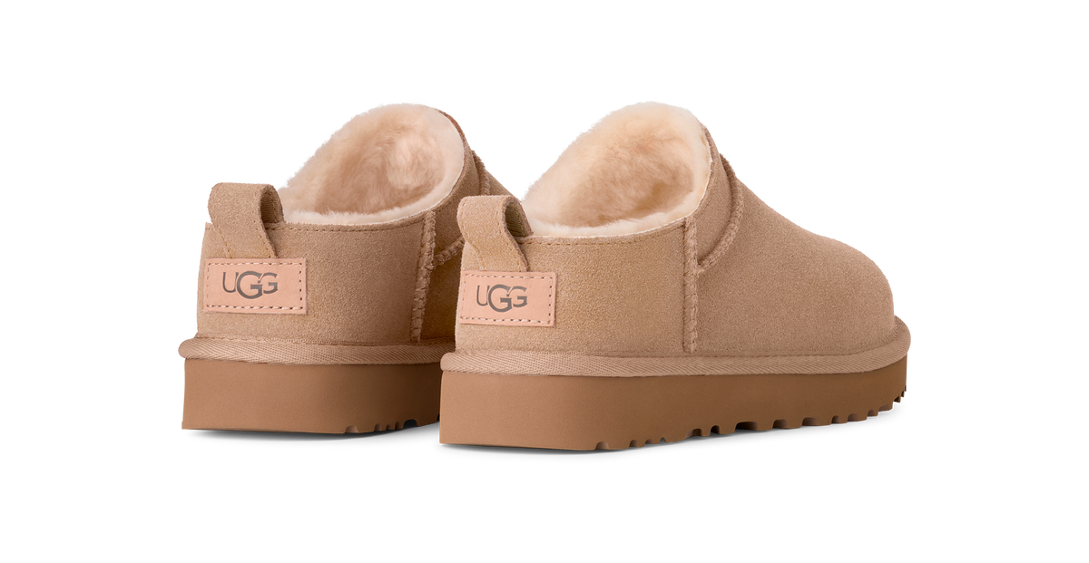 Pair of beige UGG slippers on a white background