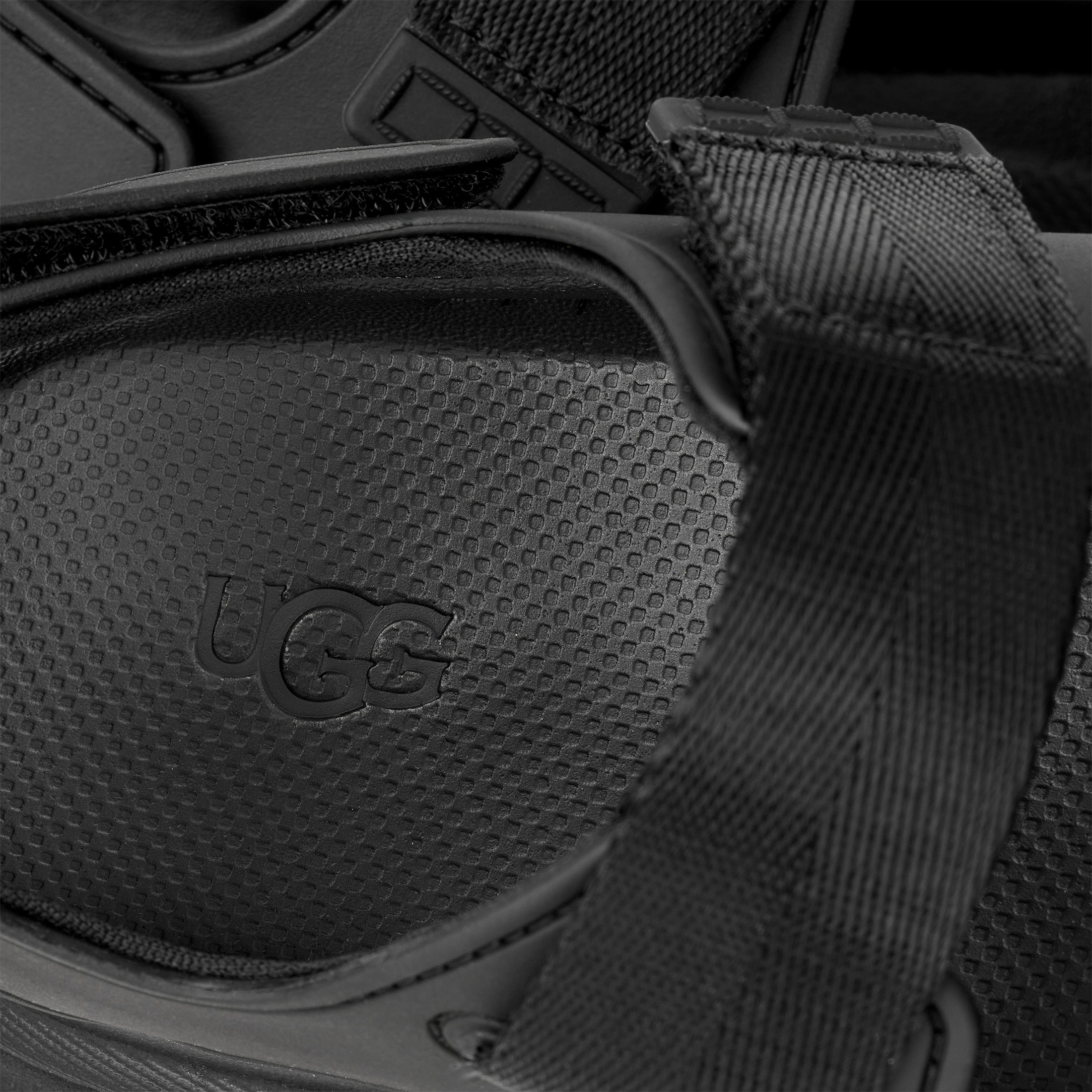 Close-up of a black UGG shoe with a textured sole and visible brand logo.
