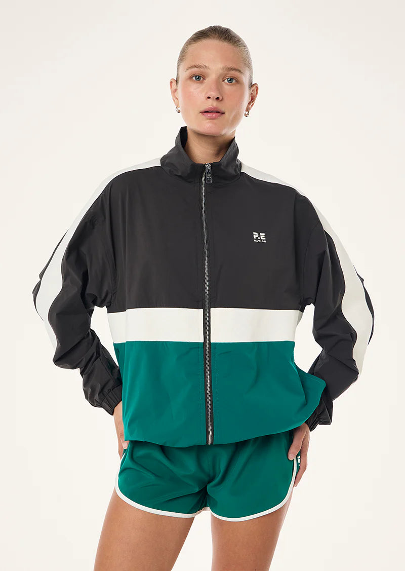 Person wearing a black and green tracksuit with a visible brand logo on a white background