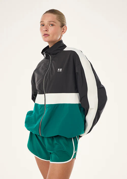 Person wearing a black and green tracksuit with a white logo on a light background