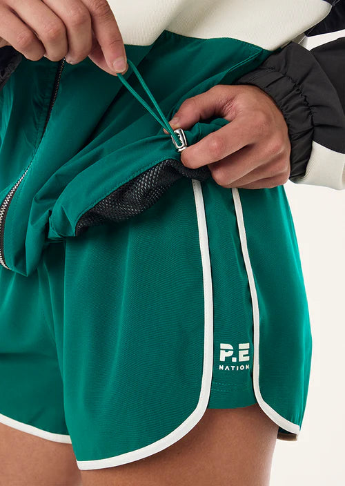 Person wearing teal shorts with a visible brand logo on a white background