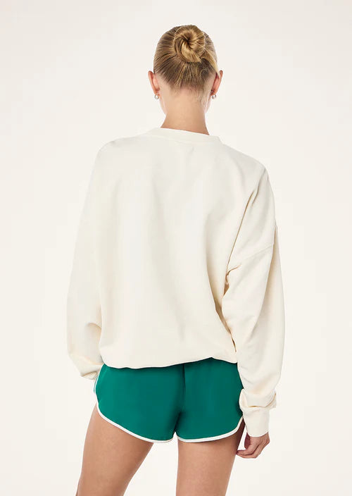 Person wearing a white sweatshirt and green shorts on a plain background