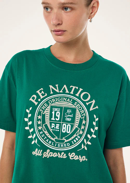 Person wearing a green t-shirt with 'P.E. Nation' logo and text.