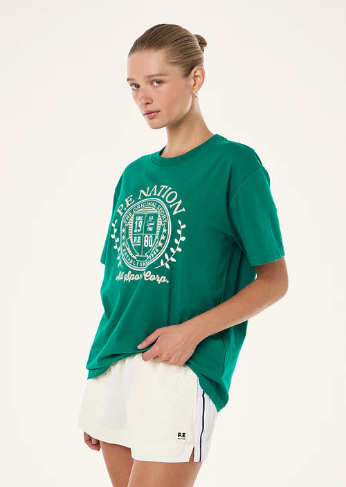 Person wearing a green t-shirt with a logo and text, standing against a white background